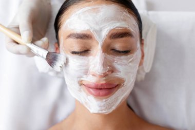 Kozmetik uzmanı, kaplıca salonundaki kadınların yüzüne beyaz maske takıyor.