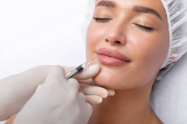 Kozmetik salonundaki dudak büyütme ve düzeltme prosedürü. Kadın hasta dudaklarına iğne yapan kadın uzmanı. Kapatma.