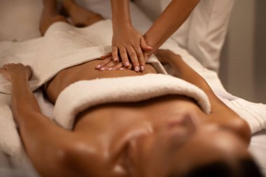 Sakince kaplıca merkezinde yatan bir kadına mide masajı yapan bir masör. Hasta ile çalışırken profesyonel doktor masörü.