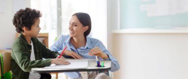 Öğretmen Latin çocuğa ilkokul, sınıf desteği, burs ve eğitimci yardımı, sınıfta erkek öğrenciye açıklama veya yardım etme konusunda yardım ediyor