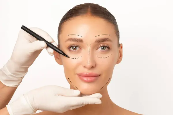 Plastik cerrahi seansına hazırlanan genç bir kadın, tıbbi eldivenli bir doktor beyaz arka planda izole edilmiş kadın hasta yüzü.