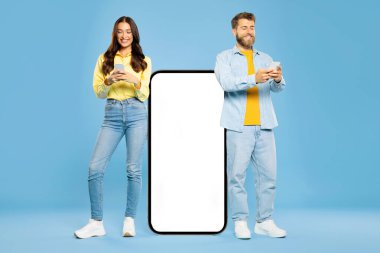 Cep telefonunun yanında boş ekranlı bir çift duruyor. İkisi de telefonlarını kullanıyor. Mavi arka planda mobil uygulama reklamları yapıyor.