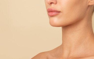 Nazik kadın boynu, dudakları ve çenesi bej renkli stüdyo arka planında izole edilmiş poz veren, serbest alan. Güzellik kavramı, doğal cilt, kozmetik bakım, spa, estetik cerrahi