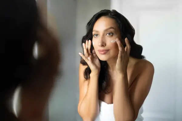 stock image Morning beauty routine. European woman touching face with fingers, applying caring skin moisturiser creme, using natural cosmetics