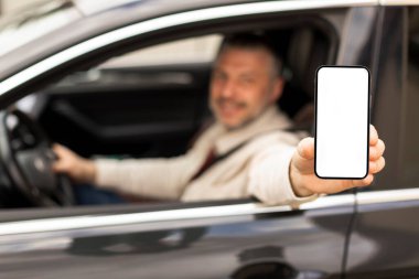 Cep telefonu boş ekranını açık araba penceresinden gösteren bir adam, seçici odaklanma. Sürücü reklamcılığı navigasyon uygulaması