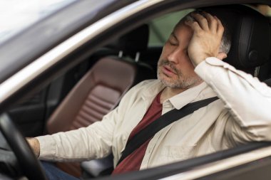 Üzgün orta yaşlı adam araba kullanıyor, yorgun ve dokunaklı, direksiyonu otomatik tutuyor.