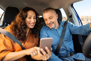 Navigasyon konsepti. Çift, arabalarında birlikte araba kullanırken cep telefonunda GPS uygulaması kullanıyor.