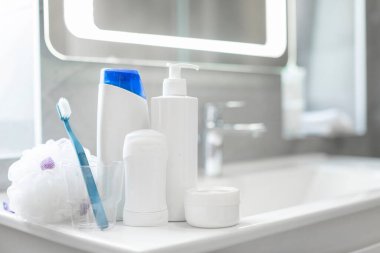Şampuan, losyon, sünger, deodorant, bir kavanoz krem ve fincanla banyo lavabosundaki diş fırçası gibi çeşitli banyo malzemeleri.