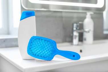 Marka tasarımlı boş şampuan şişesi ve banyo arkaplanı bulanık lavaboda saç tarağı.