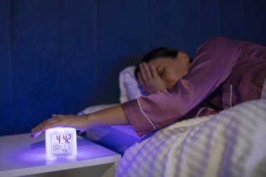 Dijital ışıklandırma alarmını kapatmak için elini uzatan kadın, sabahın erken saatlerinde çalıyor. Uyan ve acele et.