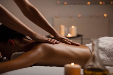 Fit bayan sırt masajı yaptırıyor, spa merkezindeki rahatlama atmosferinin keyfini çıkarıyor mumlarla süslenmiş, yan manzara, boş alan