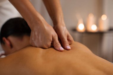 Masör terapist, spa merkezindeki genç bayana profesyonel vücut masajı yapıyor. Sade bir atmosferi var, yakın plan.