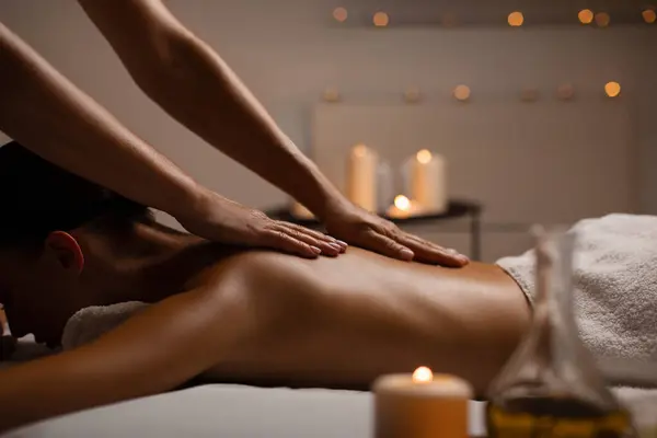 Fit bayan sırt masajı yaptırıyor, spa merkezindeki rahatlama atmosferinin keyfini çıkarıyor mumlarla süslenmiş, yan manzara, boş alan