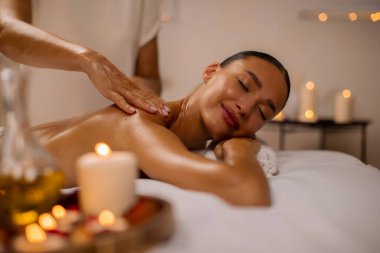 Masör arkasını sıcacık atmosferde mumlarla sımsıkı ovalarken, masaj masasında uzanan mutlu kadın, boşluğu kopyala.