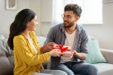 Mutlu Hintli eşler evdeki kanepede otururken hediyelerini değiş tokuş ederler, sevgi dolu bir adam heyecanlı kız arkadaşına hediye verir, birbirlerini selamlarlar.