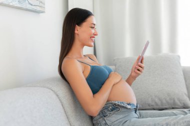 Gülümseyen, internete cep telefonuyla bakan, evdeki koltukta dinlenen, internetten alışveriş yapan ya da kocasıyla mesajlaşan bir kadın.