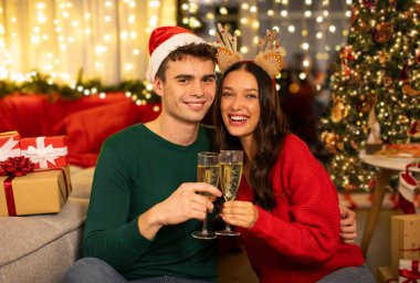Mutlu eşler ve şampanya kadehleri evde Noel 'i kutluyor, kameraya bakıyor ve gülümsüyor.