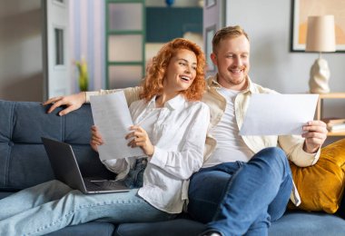 Maliye ve aile evrakları. Banka hesaplarını kontrol eden çift, mali durum ve raporlar, evdeki belgelerle birlikte dizüstü bilgisayarda bankacılık yapmak.