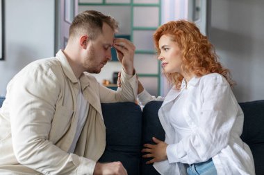 Bakıcı kadın üzgün kocayı sakinleştiriyor, oturma odasında kanepede yüz yüze oturuyor. İlişki sorunları, kötü haber tepkisi ve destek kavramı