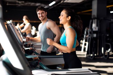 Spor salonundaki koşu bandında koşan atletik gençler, koşan erkek ve kadın, birlikte egzersiz yapan