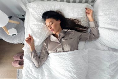 Sırt üstü uyuyan genç bir kadın, evde battaniyenin altında yatıyor, en iyi görüntü. İyi uykular.