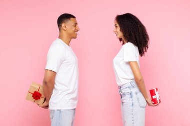 Romantik sevgililer sevgilileri sevgililer günü veya yıldönümleri için hediye saklar, tatil sürprizleri yapar, pembe stüdyo arka planında poz verirler.