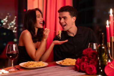 Romantik bir ilişki. Aşık çift yemek yiyor, kadın erkek arkadaşını makarna ile besliyor, aşıklar romantik anın tadını çıkarıyor.