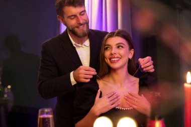 Lokantada romantik bir yemekte sürpriz kız arkadaşına lüks bir kolye sunan şefkatli bir adam. Sevgililer Günü Kutlaması