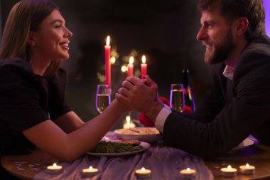 Aşk ve ilişki. Lokantada romantik bir randevuda mutlu bir çift, el ele tutuşuyorlar ve birbirlerine gülümsüyorlar.