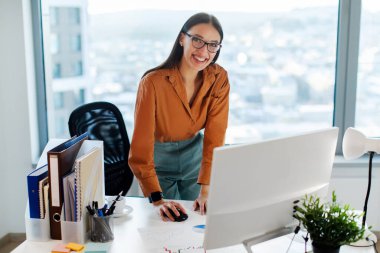 Modern ofiste çalışan neşeli Avrupalı kadın genel müdür, iş yerinin yanında duruyor ve kameraya gülümsüyor, boşluğu kopyalıyor.