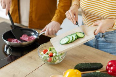 Kadın salataya taze sebze kesip ekliyor, kocasıyla yemek hazırlıyor, yakın plan.