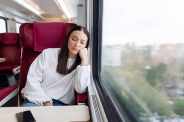 Kadın trende otururken uyuyor, dinleniyor, tatil için at sürüyor, boş yer var.