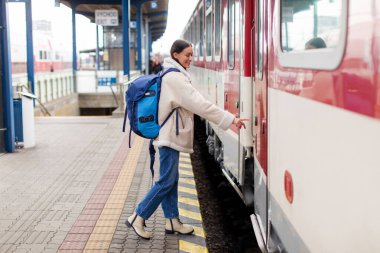 Trenin kapısındaki düğmeye basan neşeli kadının yan görüntüsü. Vagona girip açmak için. Demiryolu konsepti