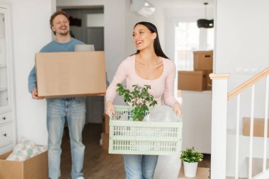 Taşınma konsepti. Genç Avrupalı çift yeni evlerine taşınırken ellerinde eşyalar taşıyor.