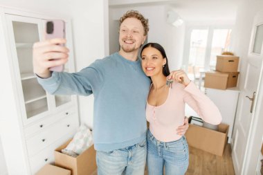 Yeni evim. Mülk sahibi olmak için anahtar gösteren mutlu eşler, taşınmak ve selfie çekmek. Yer değiştirme, yatırım ve hafıza