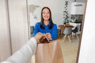 Neşeli genç bayan kapıyı açıyor ve teslimat kuryesinden sipariş alıyor apartmandaki kadın müşteriye paket veriyor.