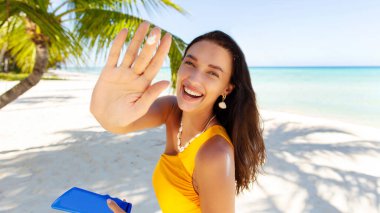 Neşeli kaygısız kadın elinde güneş kremi şişesiyle vücuduna krem ya da krem sürüyor güneşli bir yaz gününde okyanus sahilinde duruyor. Güneş koruma kavramı