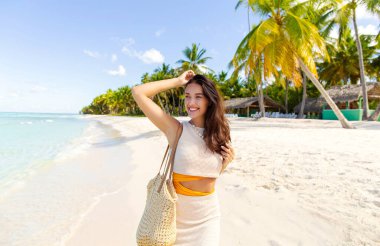 Güzel bir kadın sahilde poz veriyor ve okyanusa bakıyor, adada tropikal tatilin tadını çıkarıyor, boş bir alan.