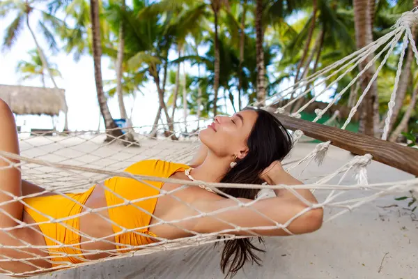 Mutlu bayan güneşleniyor ve yaz tatillerinde hamakta dinleniyor. Tropik tatil yerlerinin tadını çıkarıyor.