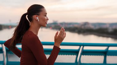 Kadın koşucu akşam antrenmanı yapıyor, koşuyor ve kulaklıkla müzik dinliyor.