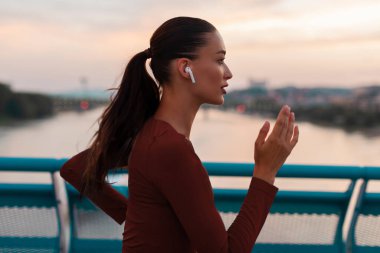 Kadın koşucu akşam antrenmanı yapıyor, koşuyor ve kulaklıkla müzik dinliyor.