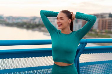 Neşeli bayan dışarıda egzersiz yapıyor, köprüde duruyor ve dışarıda egzersiz yaparken ısınıyor, boş yer var.