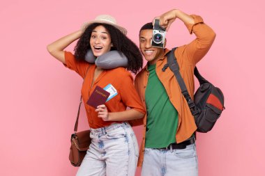 Mutlu Afrikalı Amerikalı eşler tatile hazır, elinde retro kamera olan adam, pembe arka planda poz veren kadın.