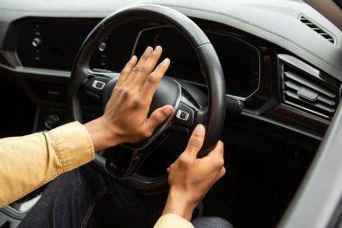 Genç siyah adam araba sürerken korna çalıyor, arabada oturuyor, direksiyonu tutuyor, otomatik olarak kornaya basıyor.