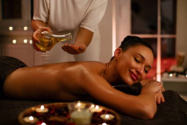 Profesyonel masözle sakin bir spa seansı. Ellerine masaj yağı dökerek rahatlatıcı bir masaj seansına hazırlanıyor.