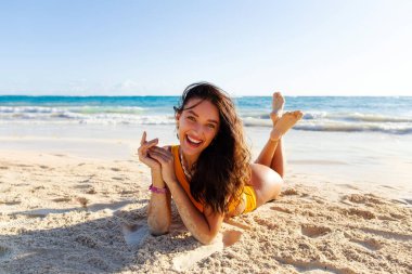 Okyanusun kenarındaki beyaz kumda turkuaz suyla yatan genç bayan, tropikal bir ülkede cennet tatili.