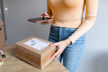 Kadın paketleri nakliye için hazırlıyor, bilgilerini akıllı telefon kullanarak belgeliyor, cep telefonu uygulaması kullanılarak paketlerin dağıtım sürecini izliyor