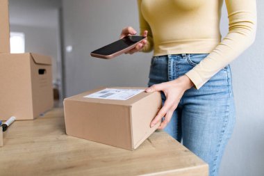 Kadın paketleri nakliye için hazırlıyor, bilgilerini akıllı telefon kullanarak belgeliyor, cep telefonu uygulaması kullanılarak paketlerin dağıtım sürecini izliyor
