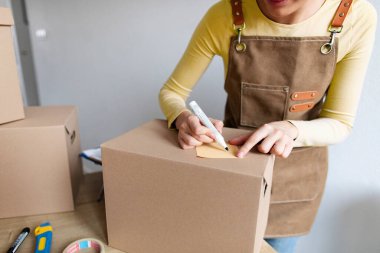Sevkiyat için kadın adres paketi, pakete iliştirilmiş etiketler hakkında yazma, iş yerinde sevkiyat için mal hazırlama veya düzenleme