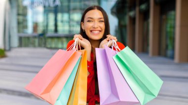 Bir sürü renkli alışveriş torbalarıyla poz veren mutlu kadın portresi indirimli satışlardan keyif alıyor. Ticaret ve başarılı alışveriş zamanı